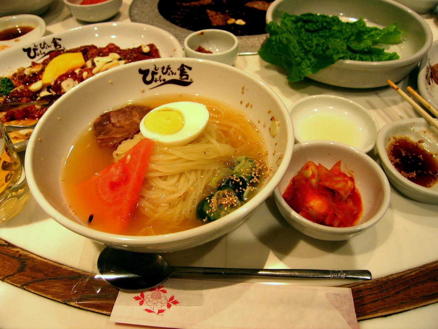 印有ぴょんぴょん舎店名的碗盛著冷麵、半顆蛋、黃瓜與西瓜,泡菜另放小碗