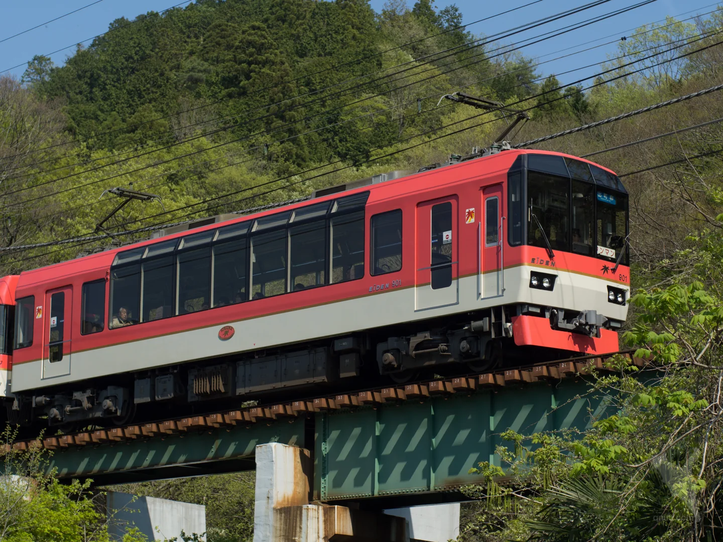 紅白色叡山電車きらら900系列車駛過市原站附近的綠色鐵橋,背後是山林。