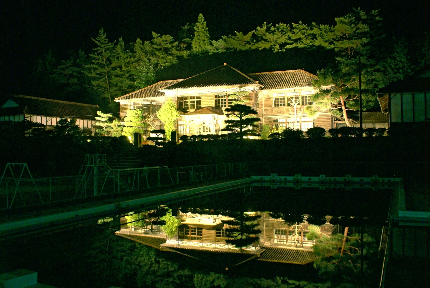 2006年吹屋小學木造本館的夜景，中央兩層校舍與前方水面倒影