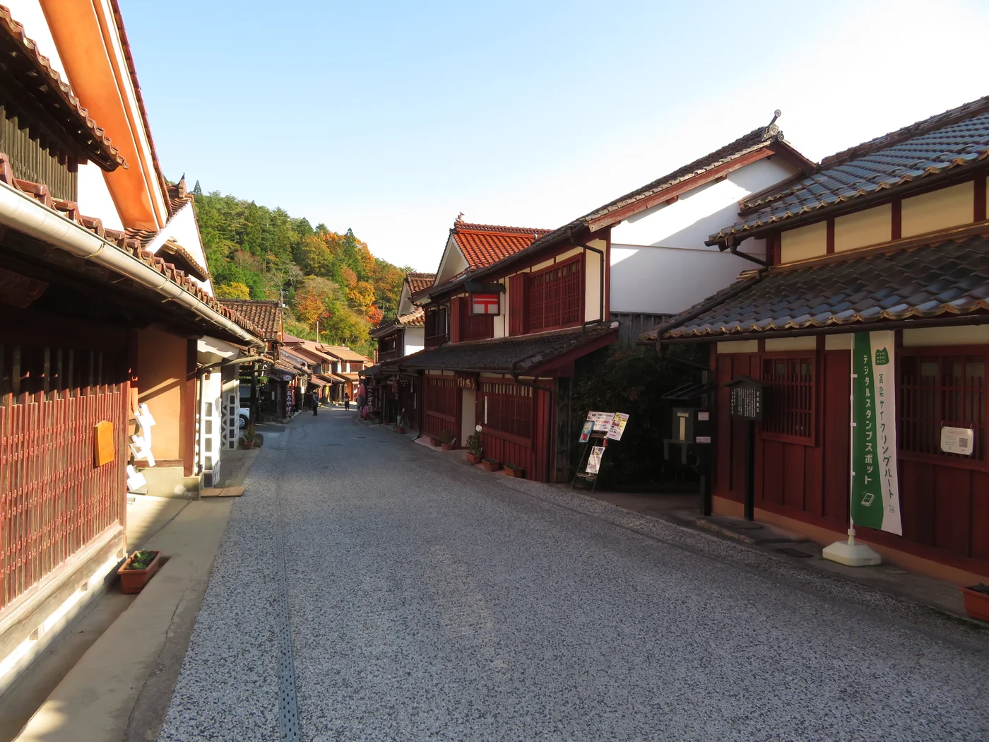 吹屋街道兩側的紅色木格和白牆，瓦屋面沿著山間街道延伸