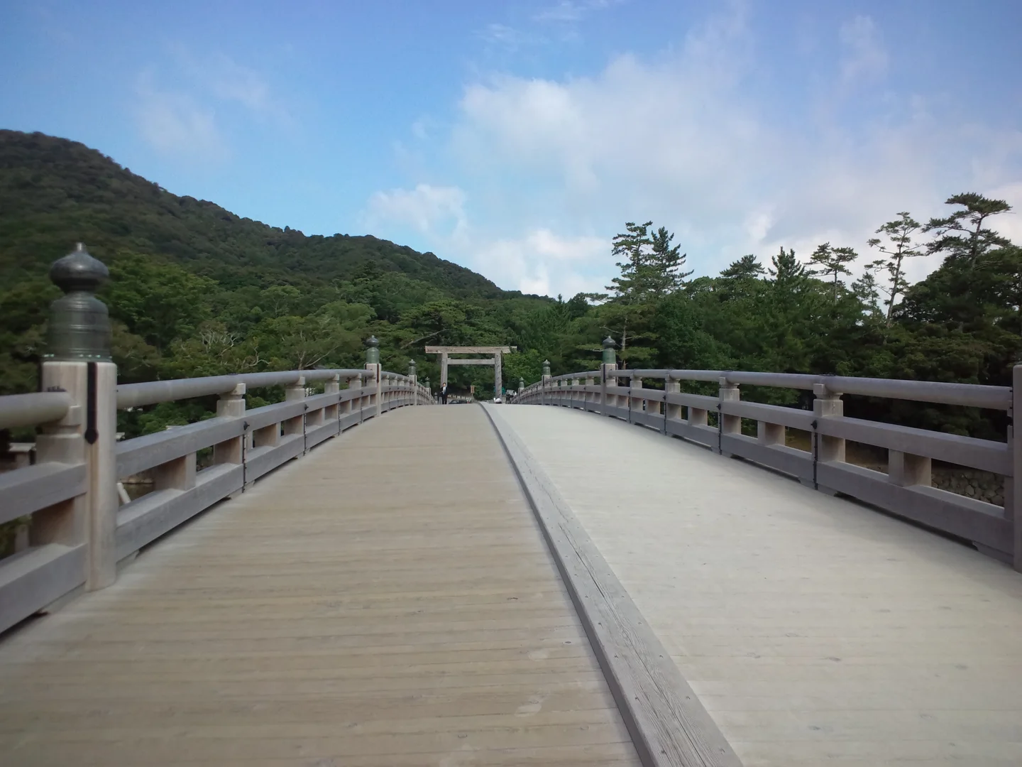 從伊勢神宮宇治橋木造橋面望向鳥居，兩側為欄杆與林木