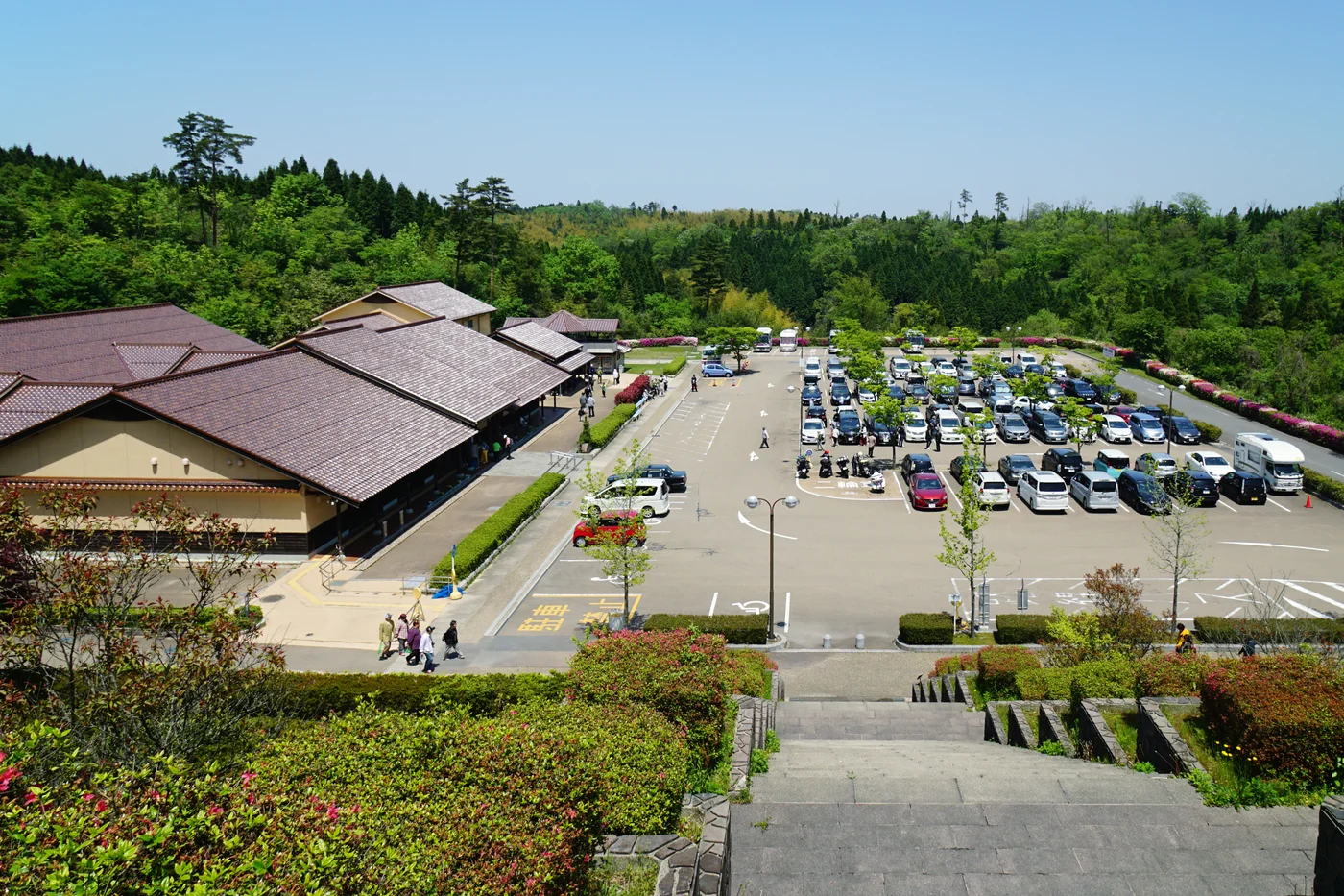 從階梯上方望向石見銀山世界遺產中心,瓦頂館舍在左側,前方是停車場與山林。