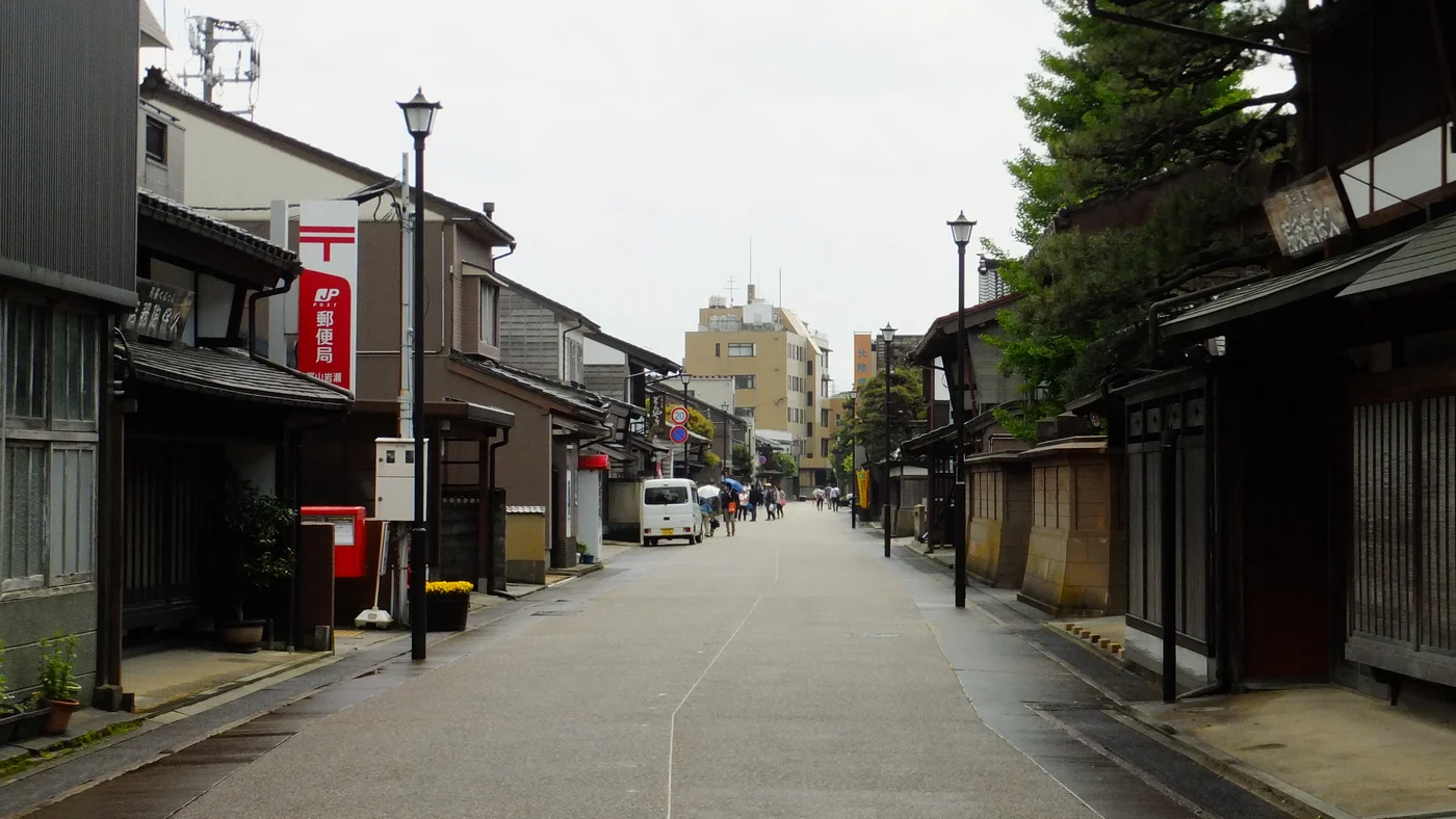 富山市岩瀨的街道,兩側木造町屋、郵局招牌與遠處行人