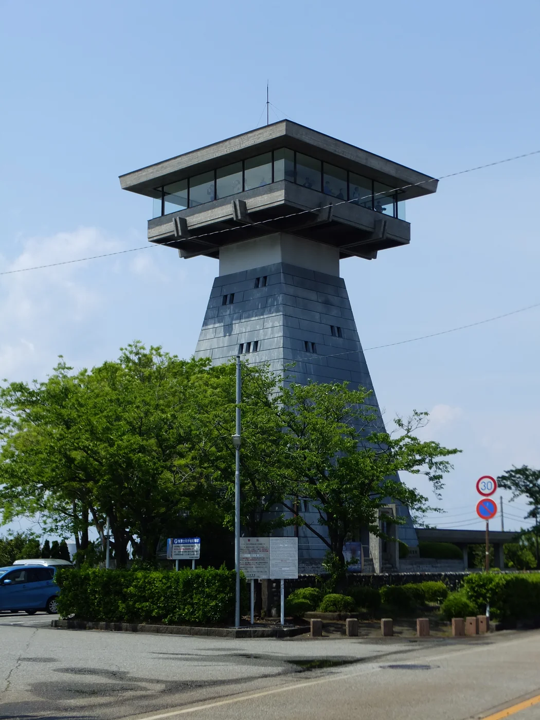 富山港展望台的高塔與上方觀景室,周圍有樹木和道路
