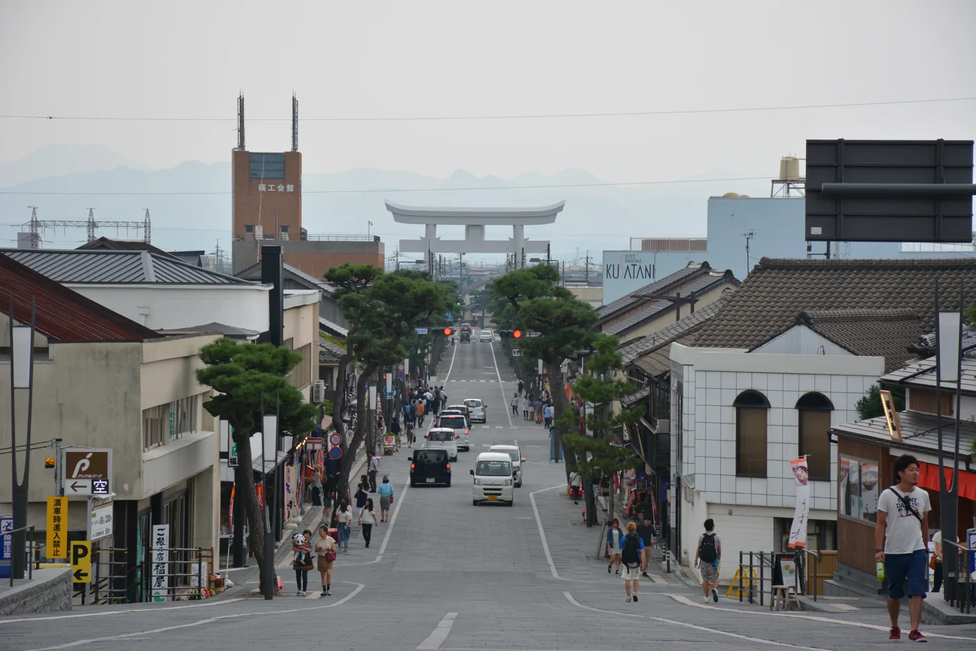 神門通沿坡向前延伸，兩側商店與行人之間可見遠方白色大鳥居