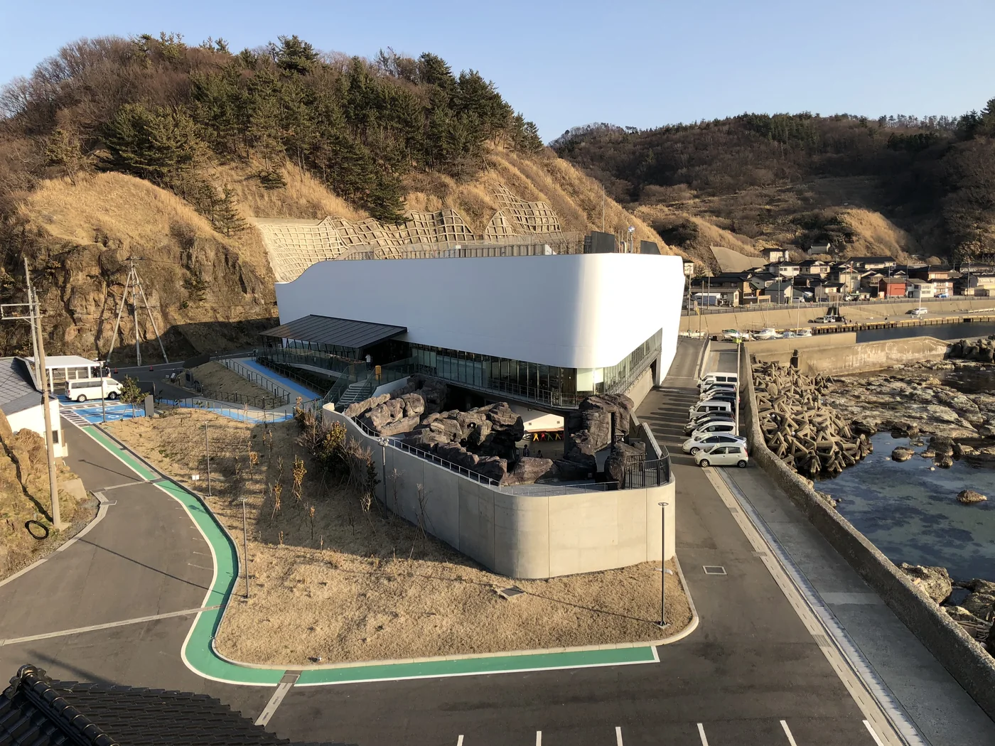 加茂水族館白色弧形外牆、館前道路與右側岩岸
