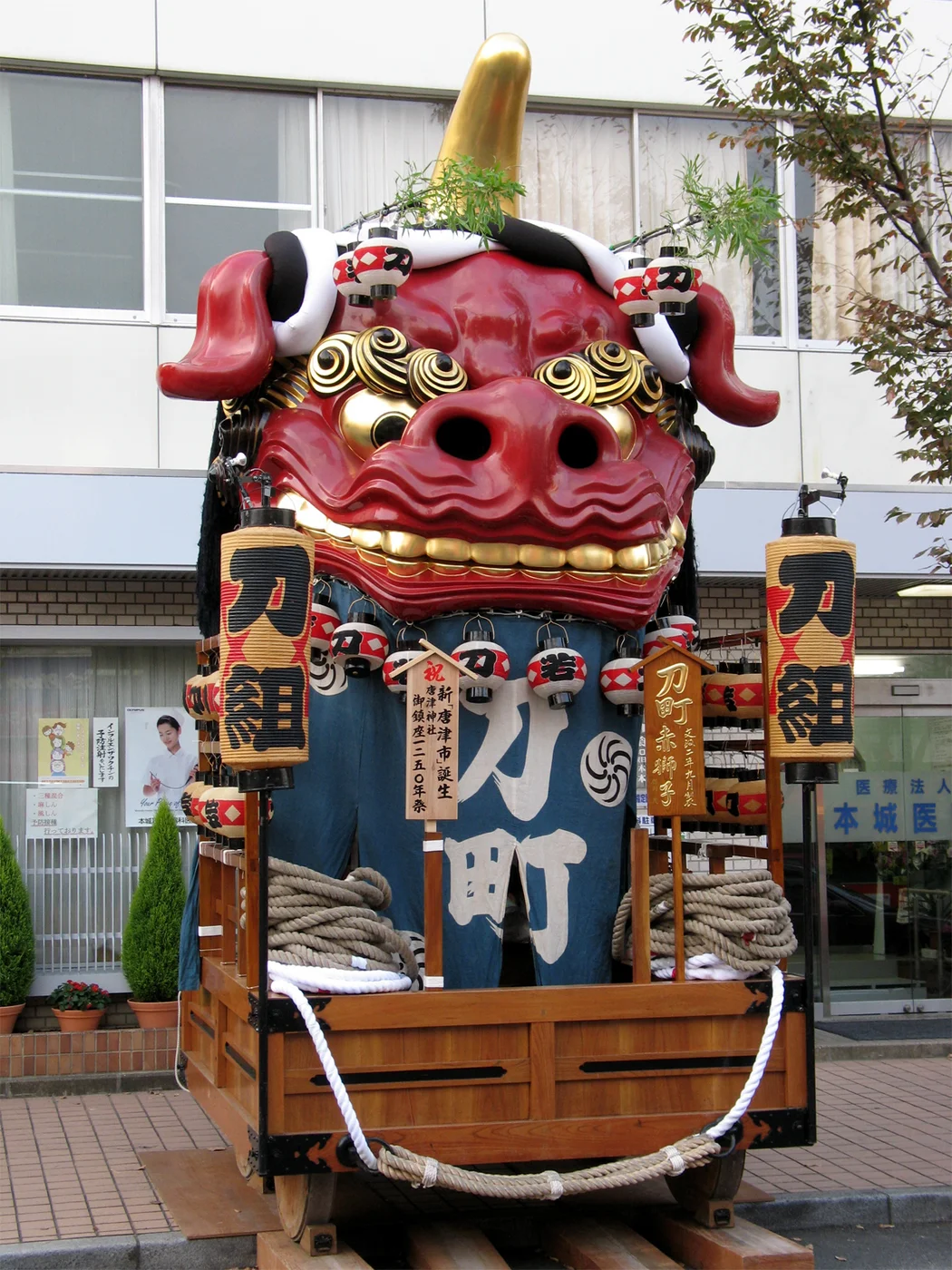 唐津くんち刀町赤獅子停在街邊,紅色獅頭、刀町提燈與木製台車