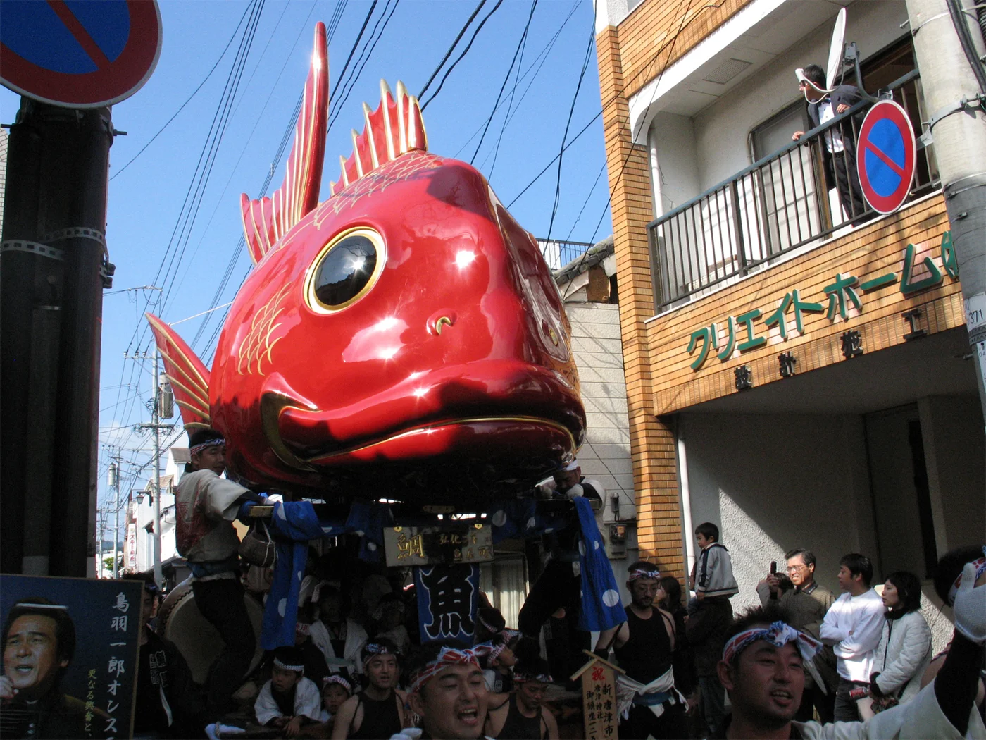 唐津くんち魚屋町的紅色鯛曳山,魚眼與魚口下方圍著曳子,街邊站著觀眾