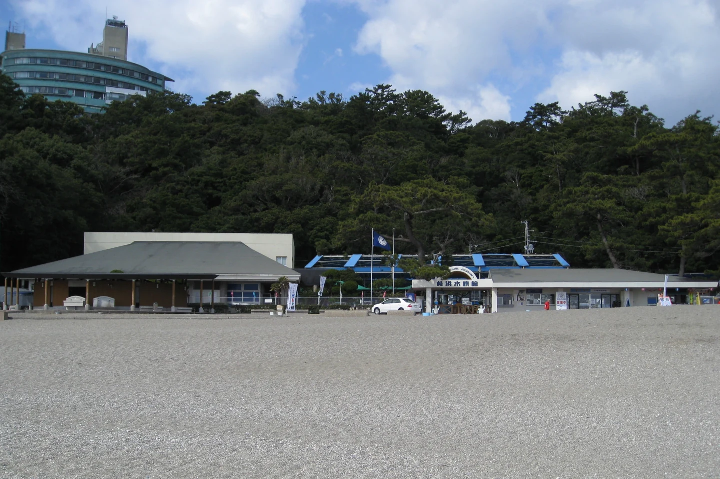 桂濱水族館低矮館舍前方為砂地，後方山坡覆蓋樹林