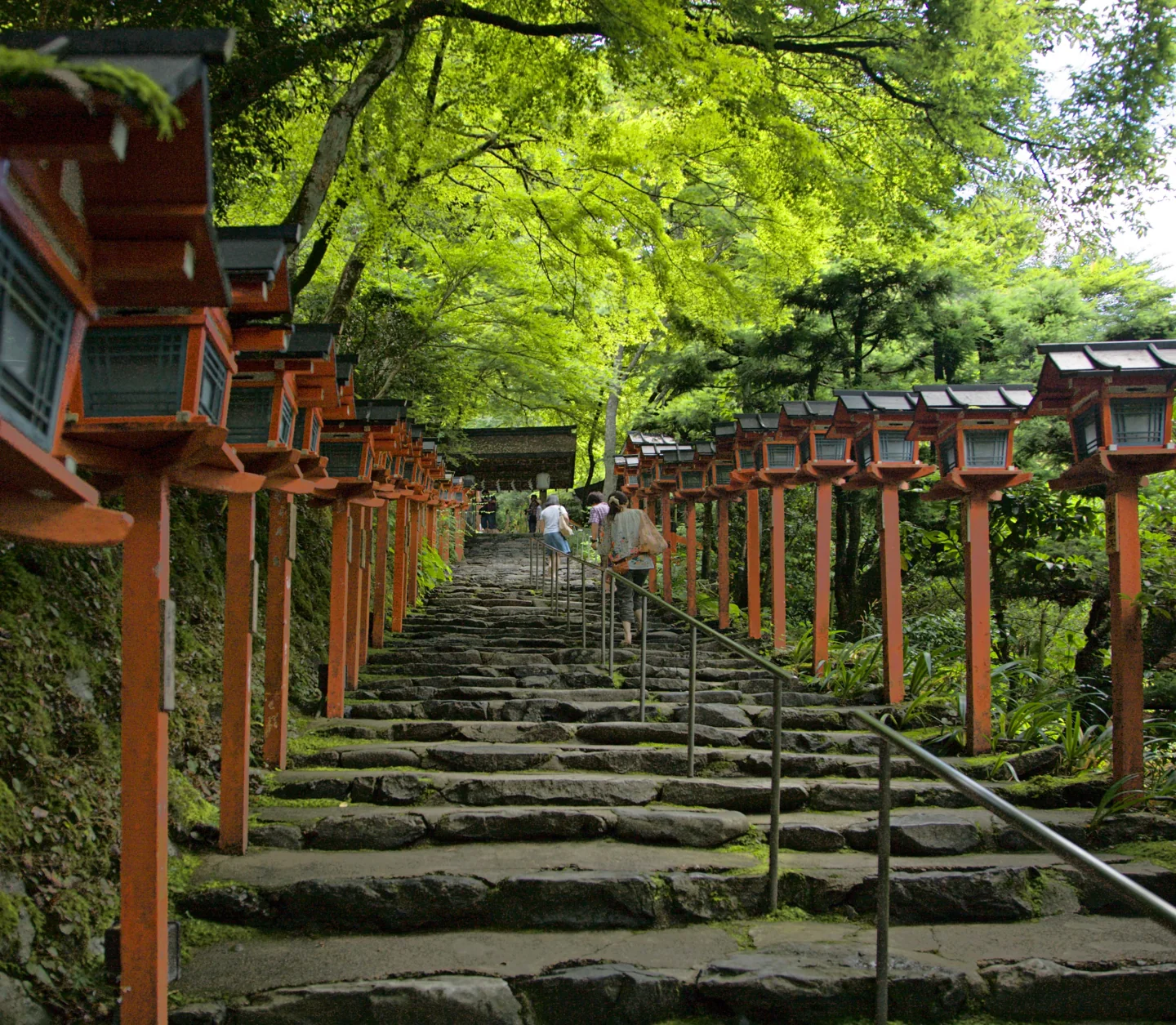 京都貴船神社本宮上行石階,兩側排列朱色燈籠,中央設有扶手。