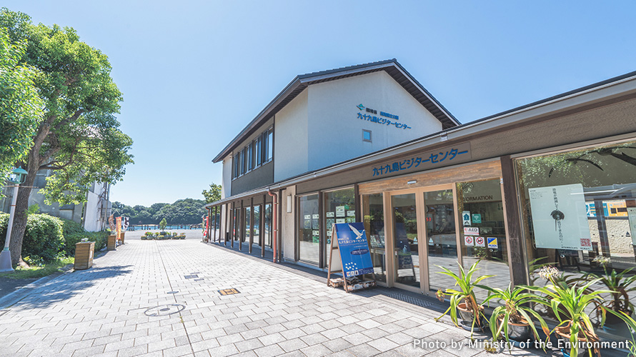 九十九島訪客中心的白色二層建物與木質入口,入口上方可見館名。