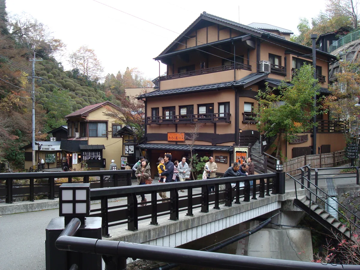 黑川溫泉丸鈴橋及橋頭的木造建築,旅人正步行通過橋面