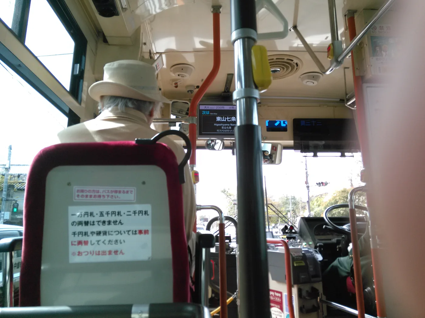 從座位後方看京都市巴士車內,前方可見扶手、駕駛區與站名顯示器