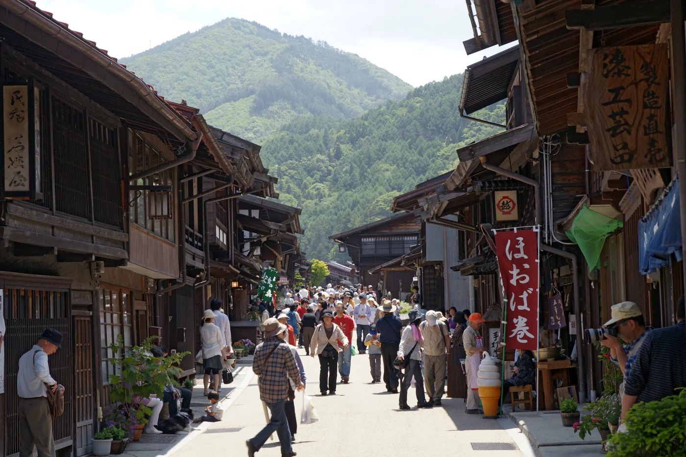 奈良井宿下町沿街的木格町家與突出屋簷,行人走在兩側店面之間