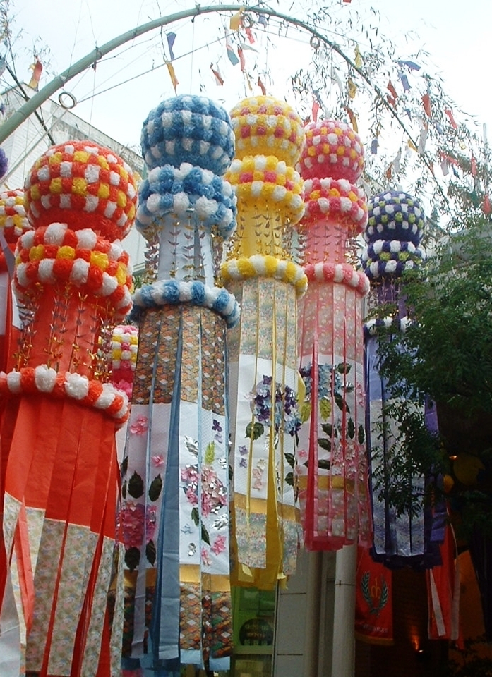 紅、藍、黃與紫色圓形紙花下垂掛長條和紙的仙台七夕裝飾