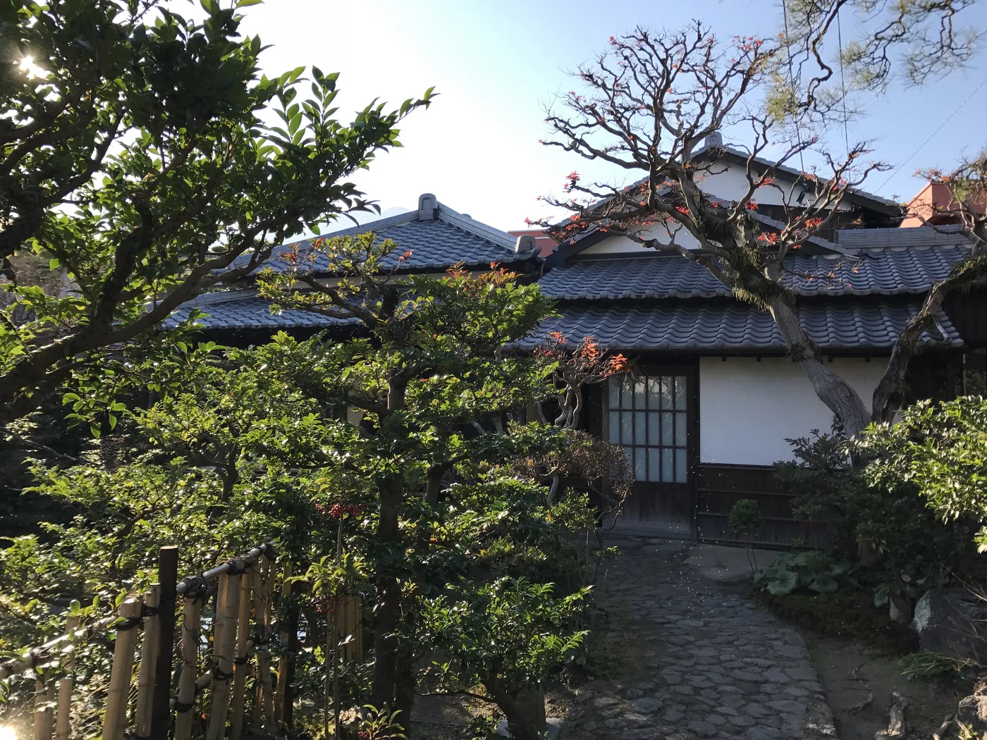 四明莊舊伊東家住宅的灰瓦屋頂、白牆與屋前庭木
