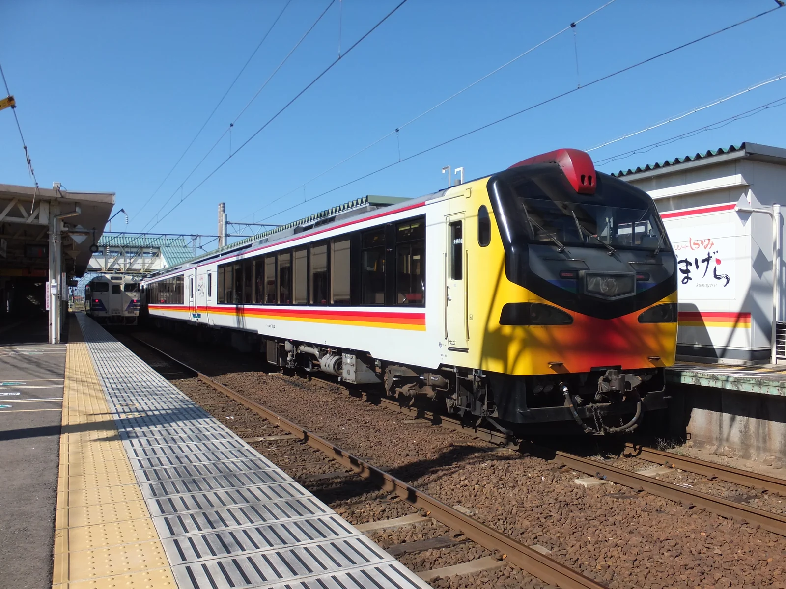 黃、橙與紅色車頭的くまげら編成停在東能代站月台