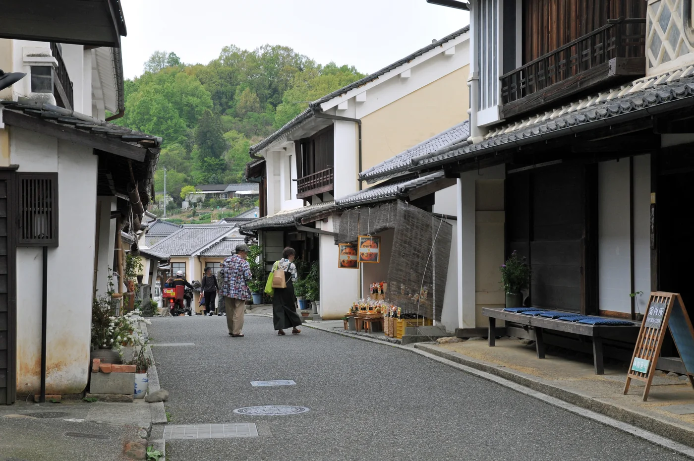 內子八日市・護國街區兩側的白牆、木造街屋與瓦屋簷,行人沿著街道散步