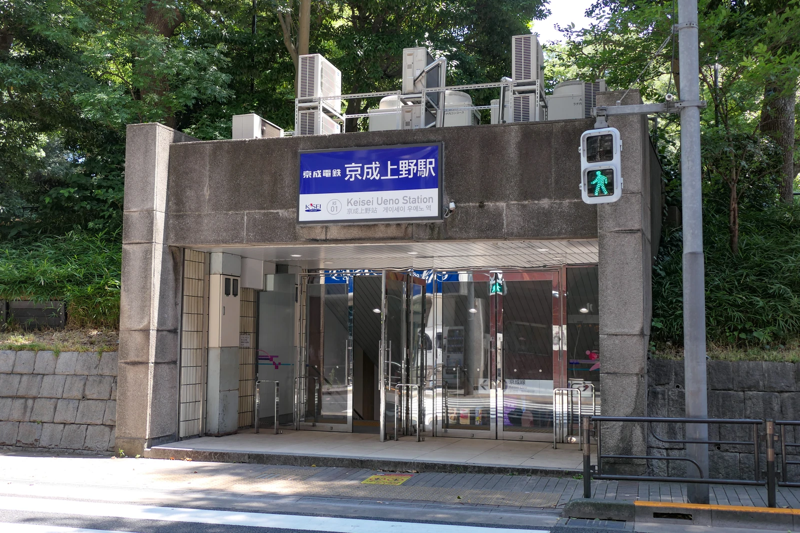 京成上野站池之端口的玻璃入口、站名牌與路旁行人號誌